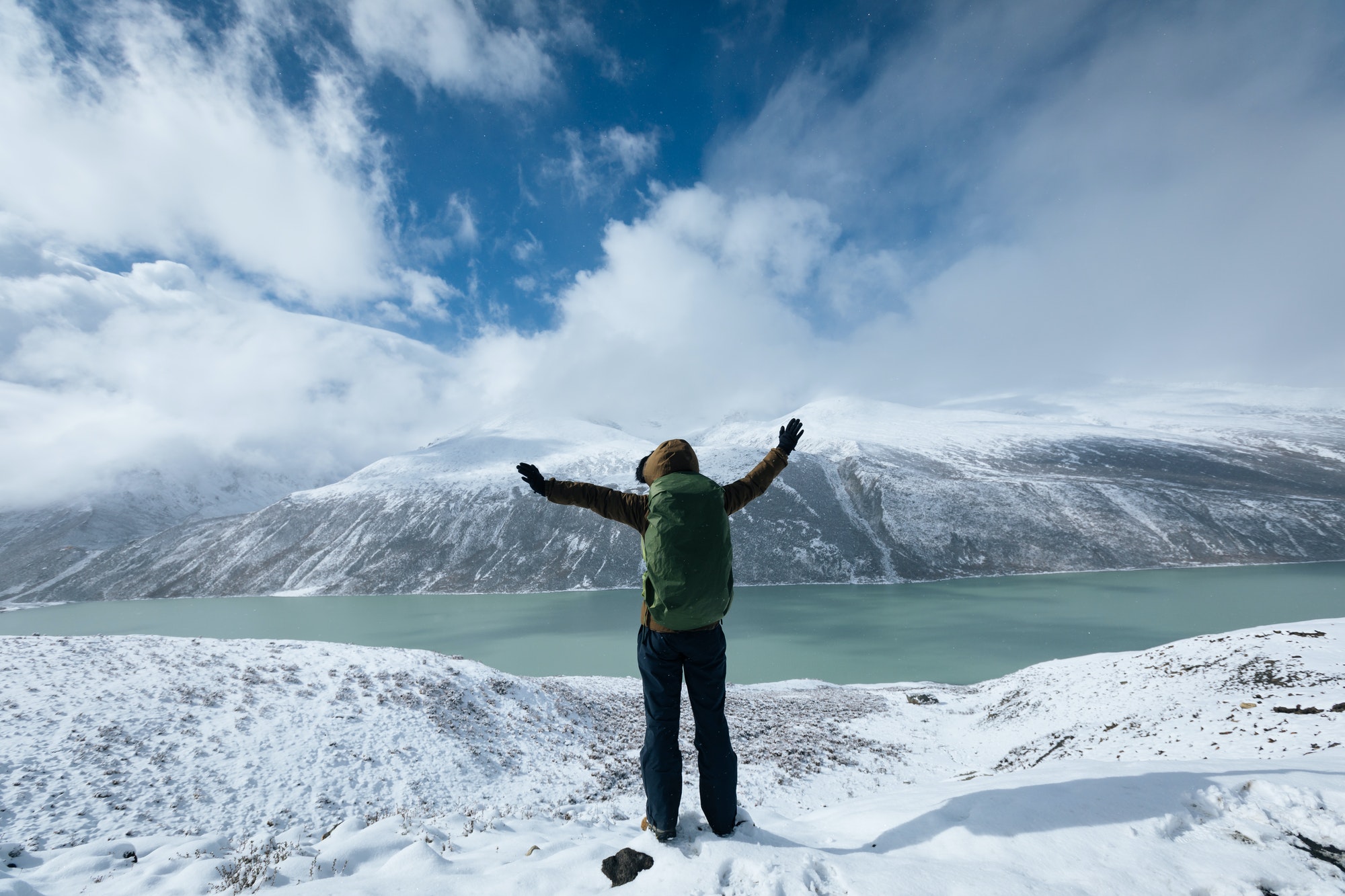 HikingCheering woman hiker hiking in snowing winter mountains